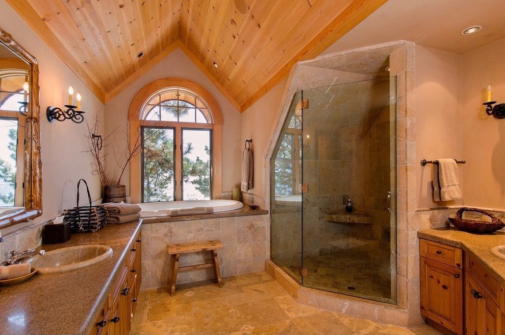 Cette image montre une douche en alcôve principale chalet avec un carrelage beige, un carrelage de pierre, un sol en travertin, un placard avec porte à panneau surélevé, une baignoire posée et un lavabo posé.