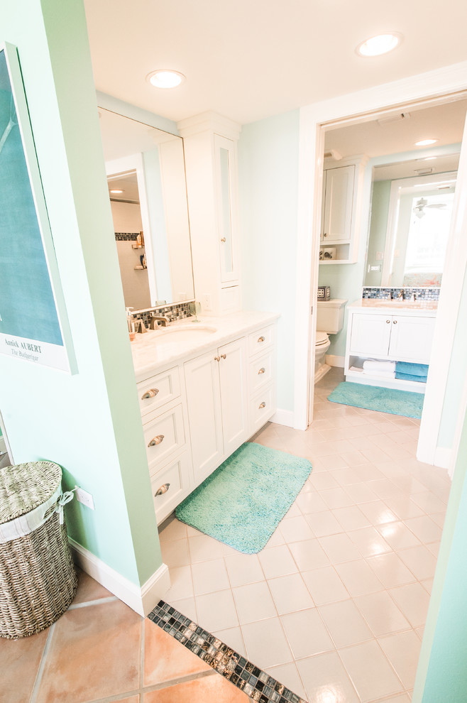 Inspiration for a mid-sized coastal 3/4 beige tile, black and white tile, brown tile and mosaic tile alcove shower remodel in Miami with recessed-panel cabinets, white cabinets, a two-piece toilet, green walls, an undermount sink and granite countertops