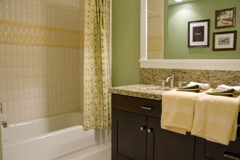 Aménagement d'une salle d'eau classique en bois foncé de taille moyenne avec un placard à porte shaker, une baignoire en alcôve, un combiné douche/baignoire, un carrelage beige, un carrelage jaune, des carreaux de porcelaine, un mur vert, un sol en carrelage de terre cuite, un lavabo encastré, un plan de toilette en granite, un sol beige et une cabine de douche avec un rideau.