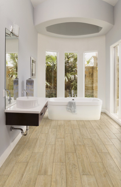 На фото: главная ванная комната среднего размера в стиле модернизм с плоскими фасадами, темными деревянными фасадами, отдельно стоящей ванной, серыми стенами, светлым паркетным полом, настольной раковиной и столешницей из искусственного кварца
