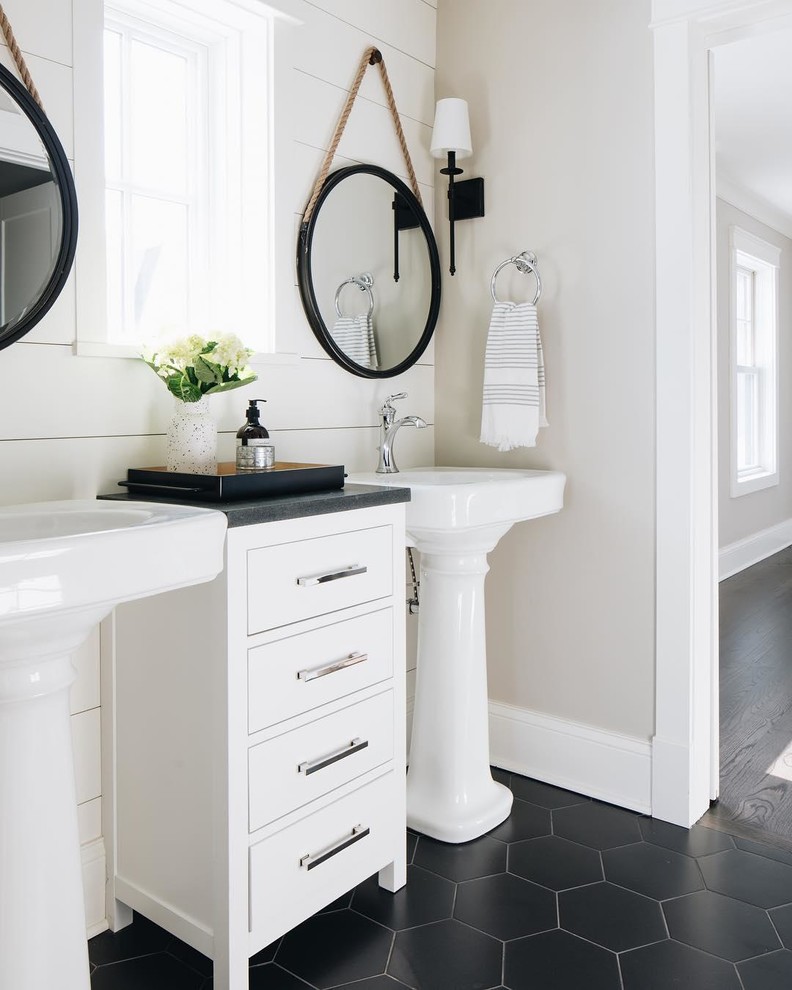 Modelo de cuarto de baño de estilo de casa de campo con paredes beige, lavabo con pedestal y suelo negro
