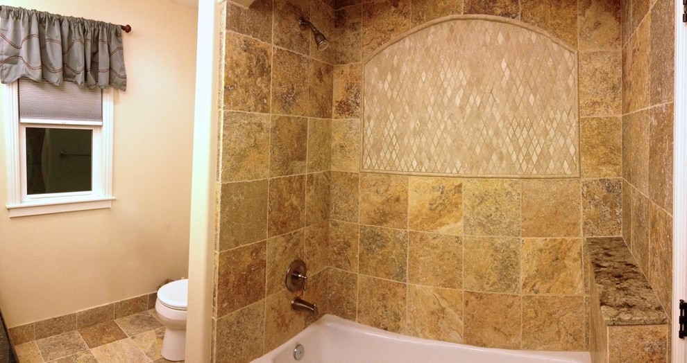Bild på ett mellanstort badrum, med ett väggmonterat handfat, luckor med upphöjd panel, skåp i mellenmörkt trä, marmorbänkskiva, ett undermonterat badkar, en dusch/badkar-kombination, en toalettstol med hel cisternkåpa, grå kakel, beige väggar och klinkergolv i keramik