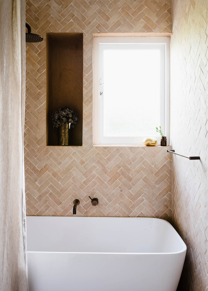 Esempio di una stanza da bagno con doccia contemporanea di medie dimensioni con consolle stile comò, ante in legno chiaro, vasca freestanding, piastrelle beige, piastrelle in pietra e top piastrellato