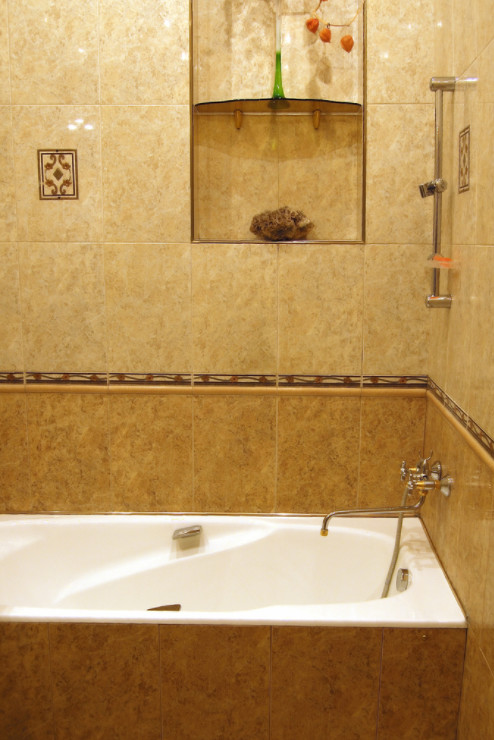 Cette photo montre une douche en alcôve principale bord de mer de taille moyenne avec une baignoire en alcôve, un carrelage beige, des carreaux de porcelaine et un mur beige.