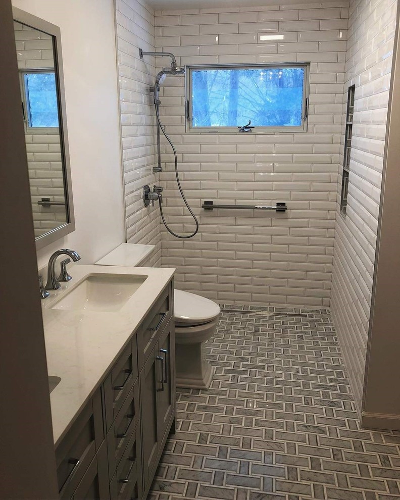 Example of a mid-sized trendy master white tile and porcelain tile marble floor and gray floor walk-in shower design in New York with shaker cabinets, gray cabinets, a two-piece toilet, white walls, quartz countertops and white countertops