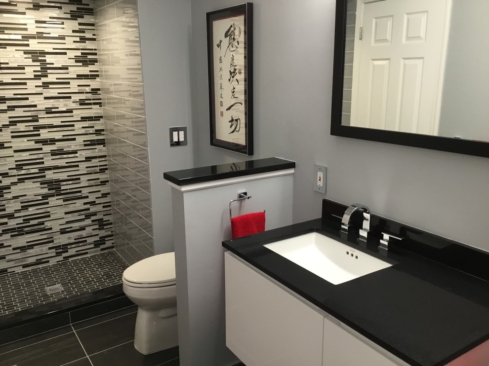 Photo of a small contemporary shower room bathroom in Detroit with flat-panel cabinets, white cabinets, an alcove shower, a one-piece toilet, black and white tiles, glass tiles, grey walls, porcelain flooring, a submerged sink, granite worktops, black floors and a hinged door.