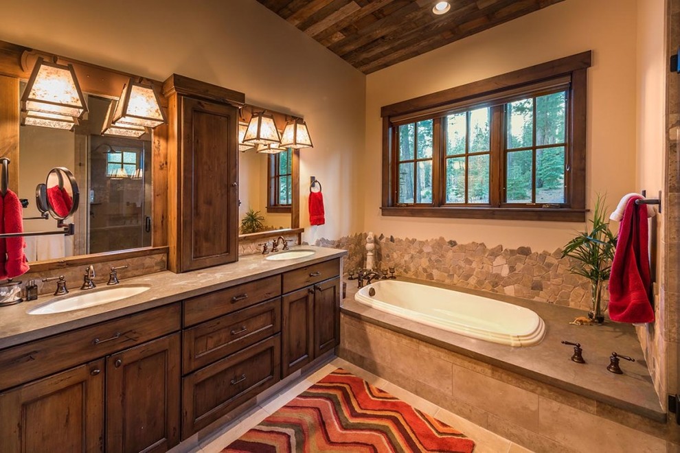 Bild på ett mellanstort rustikt en-suite badrum, med skåp i mörkt trä, ett platsbyggt badkar, beige kakel, stenkakel, beige väggar, luckor med infälld panel, travertin golv och ett undermonterad handfat
