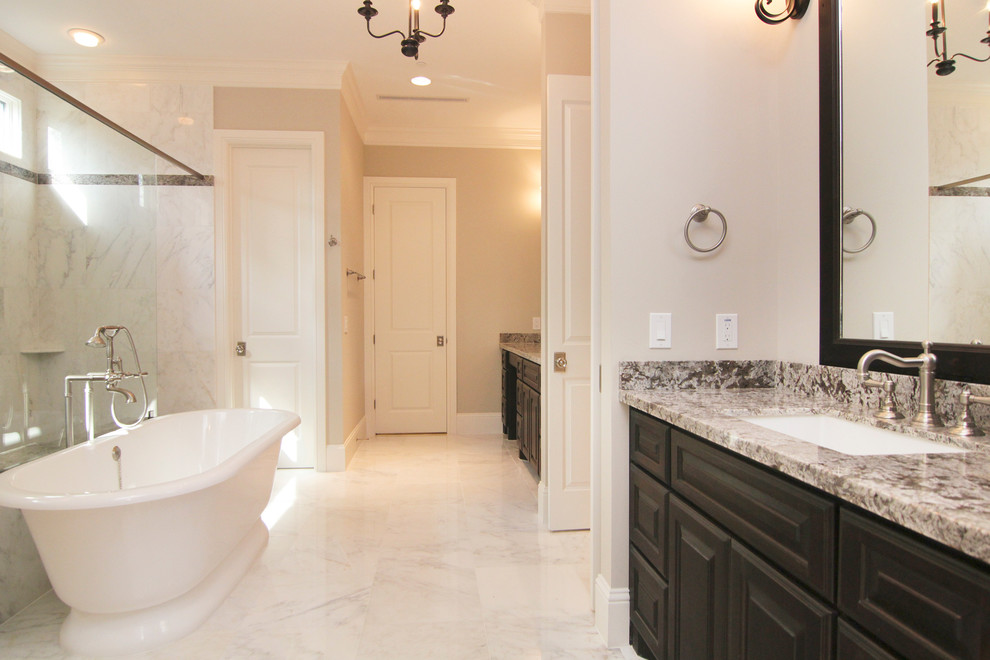 Inspiration for a large transitional master gray tile and stone tile marble floor bathroom remodel in Houston with raised-panel cabinets, dark wood cabinets, beige walls, an undermount sink and granite countertops