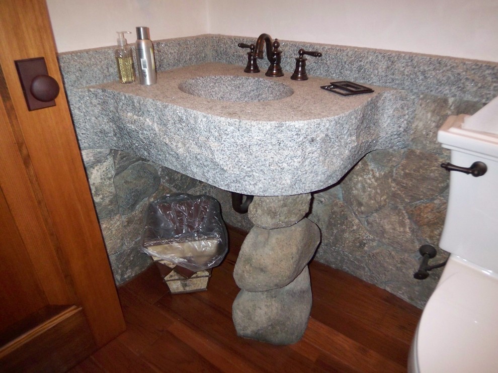 Cette image montre une petite salle de bain chalet pour enfant avec un lavabo intégré, un plan de toilette en granite, un mur blanc et un sol en bois brun.