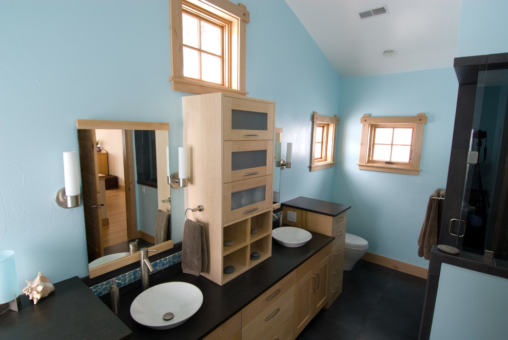 Cette image montre une petite douche en alcôve principale craftsman en bois clair avec un placard avec porte à panneau encastré, WC à poser, un mur bleu, un sol en linoléum, une vasque, un plan de toilette en surface solide, un sol noir et une cabine de douche à porte battante.