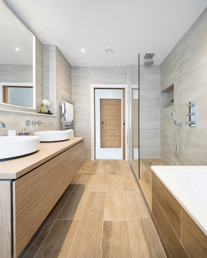 На фото: большая ванная комната в современном стиле с плоскими фасадами, угловой ванной, душевой комнатой, коричневым полом, светлыми деревянными фасадами, бежевой плиткой, бежевыми стенами, душевой кабиной, настольной раковиной и открытым душем