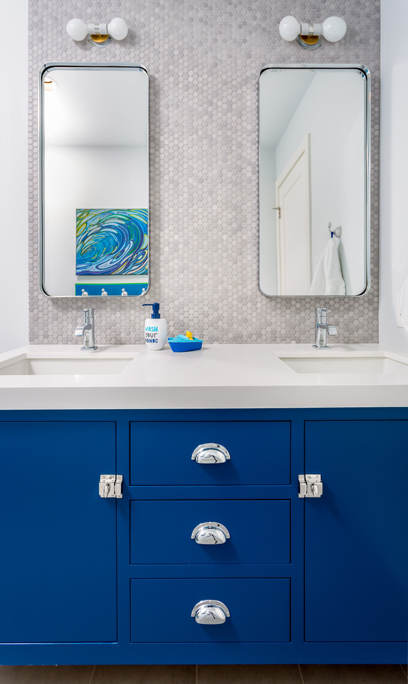 Exemple d'une salle de bain tendance de taille moyenne pour enfant avec un placard à porte plane, des portes de placard bleues, une baignoire indépendante, un combiné douche/baignoire, WC à poser, un carrelage gris, des carreaux de porcelaine, un mur bleu, un sol en carrelage de porcelaine, un lavabo encastré et un plan de toilette en quartz modifié.
