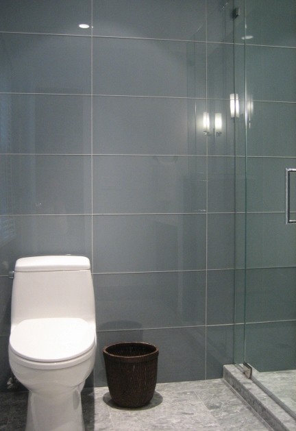 This is an example of a small modern shower room bathroom in Other with flat-panel cabinets, dark wood cabinets, an alcove shower, a one-piece toilet, blue tiles, glass tiles, white walls, marble flooring, a submerged sink and solid surface worktops.