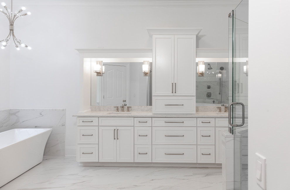 Example of a huge trendy master white tile and marble tile porcelain tile and white floor freestanding bathtub design in Atlanta with recessed-panel cabinets, white cabinets, a two-piece toilet, white walls, an undermount sink and quartz countertops