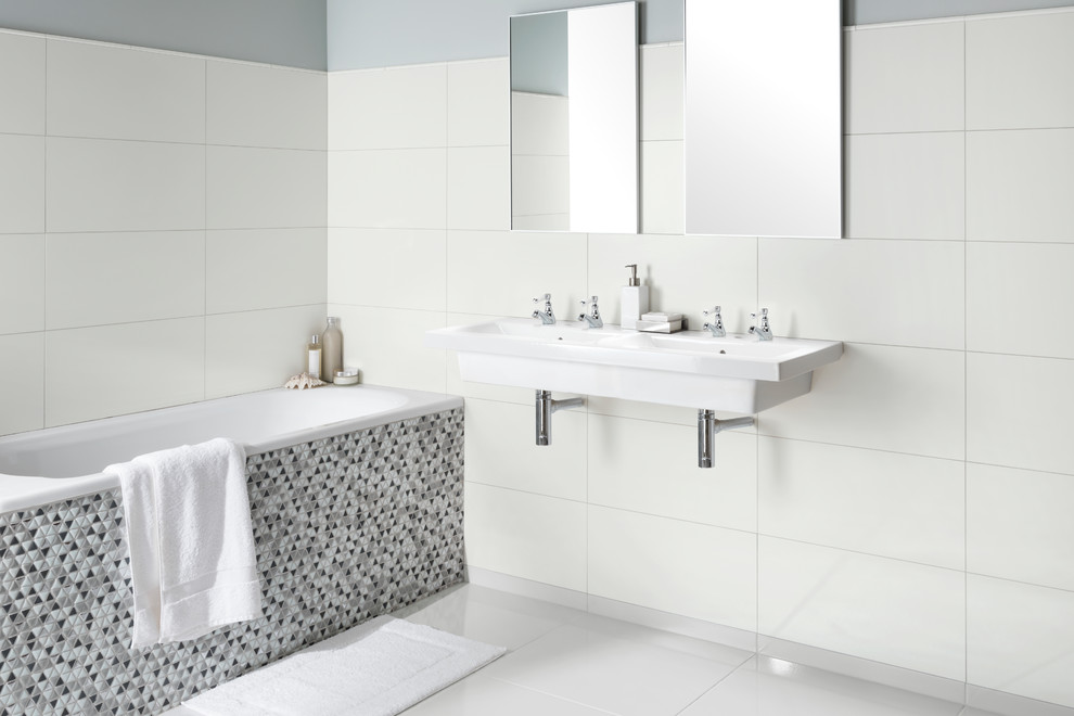 Idée de décoration pour une salle de bain design avec une baignoire posée, un carrelage blanc, des carreaux de porcelaine, un mur gris, un sol en carrelage de porcelaine et un lavabo suspendu.