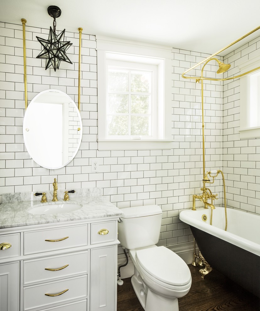 Idéer för ett klassiskt vit badrum med dusch, med luckor med infälld panel, vita skåp, ett badkar med tassar, en dusch/badkar-kombination, en toalettstol med separat cisternkåpa, vit kakel, tunnelbanekakel, mörkt trägolv, ett undermonterad handfat, brunt golv och dusch med duschdraperi