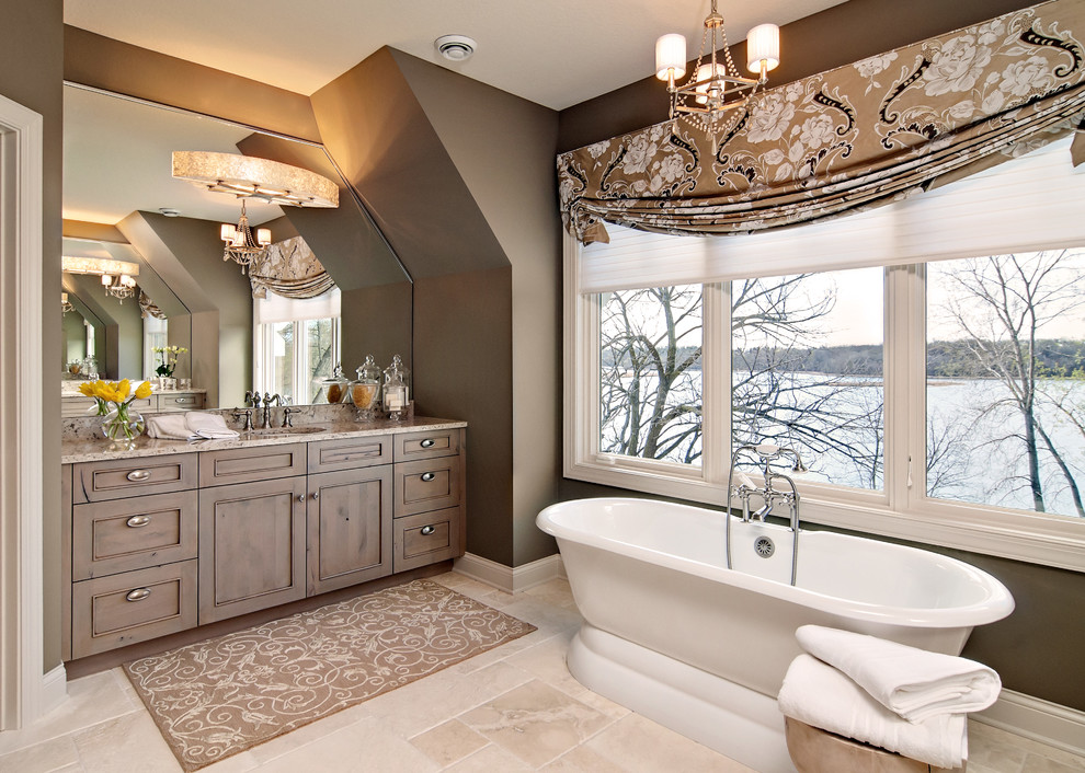 Inredning av ett klassiskt stort en-suite badrum, med ett fristående badkar, bruna väggar, luckor med profilerade fronter, skåp i mellenmörkt trä, travertin golv, ett undermonterad handfat och granitbänkskiva