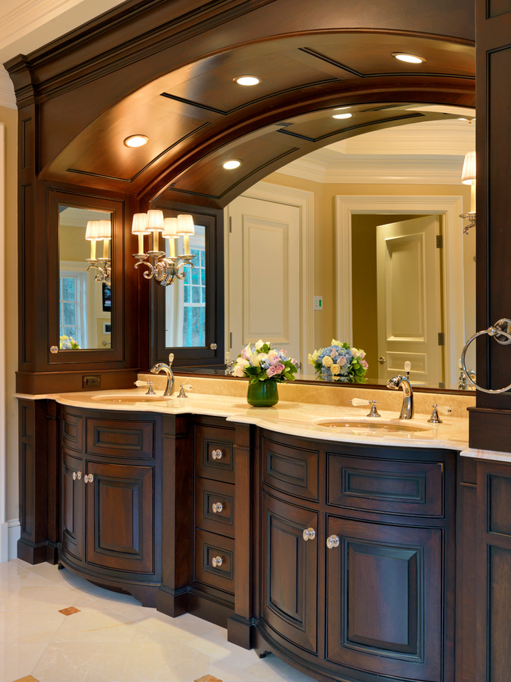 Diseño de cuarto de baño tradicional con lavabo bajoencimera, armarios con paneles con relieve, puertas de armario de madera en tonos medios y encimera de mármol