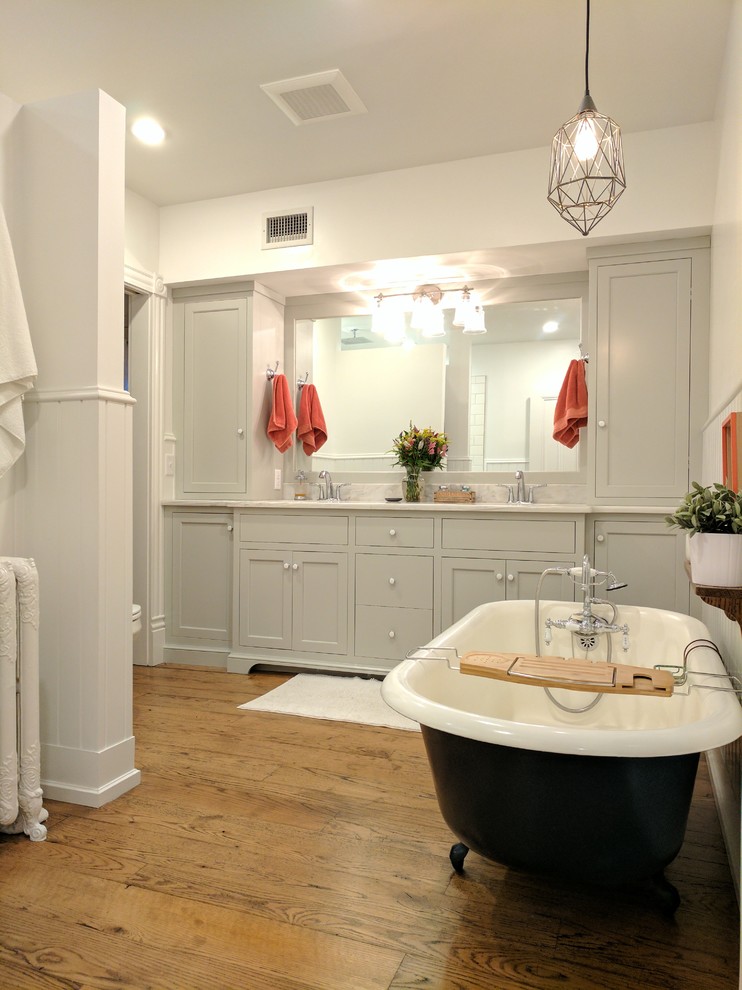 Mid-sized elegant master medium tone wood floor and brown floor bathroom photo in Philadelphia with shaker cabinets, gray cabinets, a one-piece toilet, white walls, an undermount sink and marble countertops