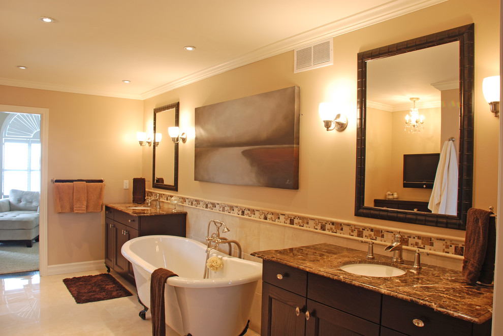 Inredning av ett klassiskt stort en-suite badrum, med ett undermonterad handfat, luckor med infälld panel, skåp i mörkt trä, marmorbänkskiva, ett fristående badkar, en dusch i en alkov, beige kakel, porslinskakel, beige väggar och marmorgolv