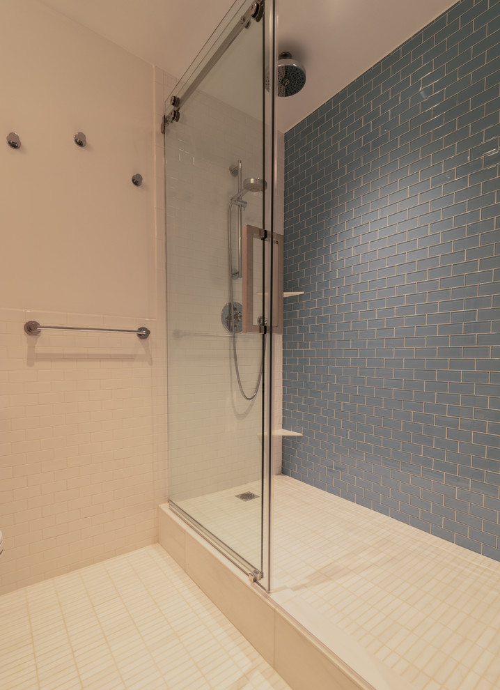 Exempel på ett modernt badrum med dusch, med släta luckor, skåp i ljust trä, en dusch i en alkov, en toalettstol med separat cisternkåpa, vit kakel, cementkakel, blå väggar, klinkergolv i keramik, ett konsol handfat, vitt golv och dusch med skjutdörr