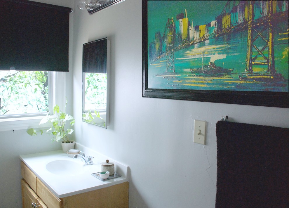 Cette image montre une petite salle de bain bohème en bois clair avec un plan vasque, un placard à porte plane, un plan de toilette en surface solide, une baignoire en alcôve, un combiné douche/baignoire, WC à poser, un mur gris et un sol en linoléum.