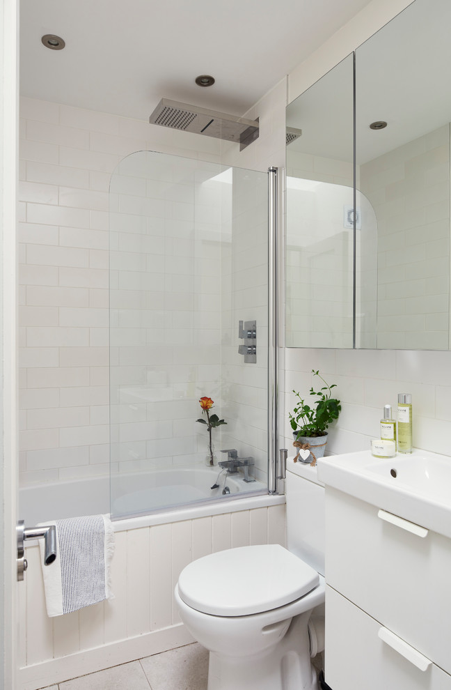 Design ideas for a contemporary family bathroom in Dublin with glass-front cabinets, white cabinets, a built-in bath, a shower/bath combination, a one-piece toilet, white walls, ceramic flooring, a wall-mounted sink, white floors and a hinged door.