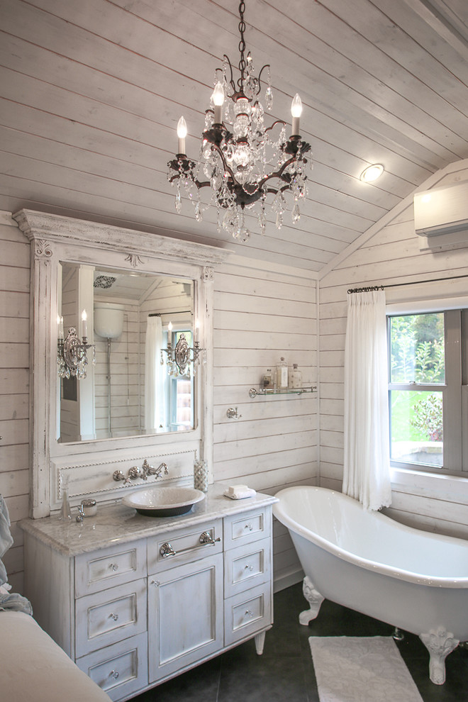 Cette image montre une petite salle de bain principale style shabby chic en bois vieilli avec une vasque, un placard à porte plane, un plan de toilette en marbre, une baignoire sur pieds, un carrelage noir, des carreaux de porcelaine, un mur blanc et un sol en carrelage de céramique.