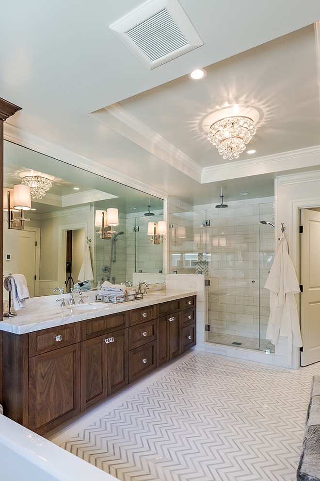 Idées déco pour une salle de bain principale classique en bois foncé avec une baignoire indépendante, une douche d'angle, un lavabo encastré, un mur beige, une cabine de douche à porte battante, un plan de toilette en marbre, un sol blanc et un placard à porte shaker.
