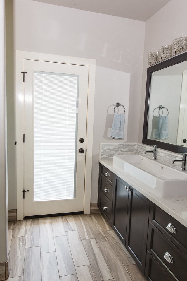 Bild på ett stort vintage en-suite badrum, med luckor med infälld panel, skåp i mörkt trä, grå kakel, vit kakel, stickkakel, vita väggar, plywoodgolv, ett avlångt handfat, bänkskiva i kvartsit och en dusch i en alkov