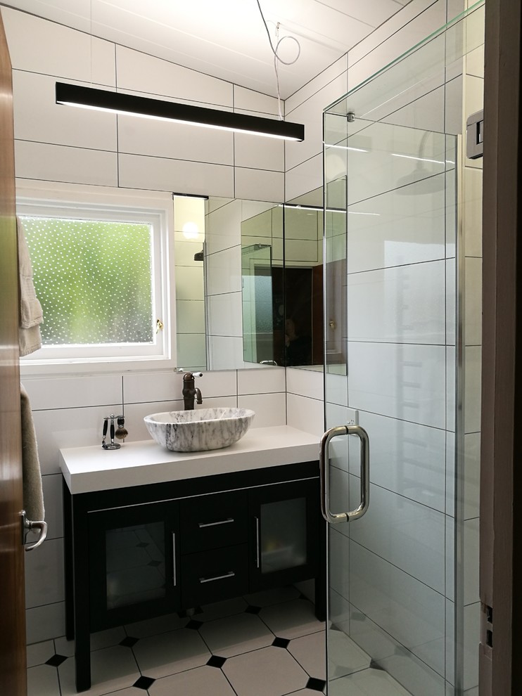 Inspiration for a small contemporary ensuite bathroom in Wellington with flat-panel cabinets, dark wood cabinets, a corner shower, white tiles, ceramic tiles, porcelain flooring, a vessel sink, engineered stone worktops, multi-coloured floors, a hinged door and white worktops.