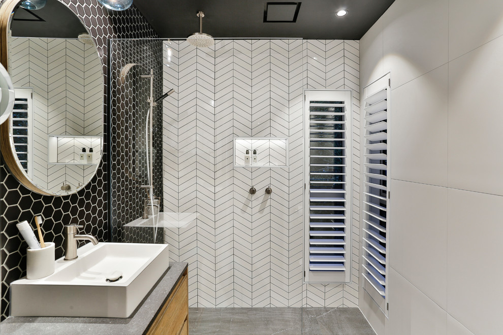 Inredning av ett modernt litet grå grått en-suite badrum, med skåp i mellenmörkt trä, en kantlös dusch, svart och vit kakel, porslinskakel, klinkergolv i porslin, ett fristående handfat, bänkskiva i kvarts, grått golv, med dusch som är öppen och släta luckor