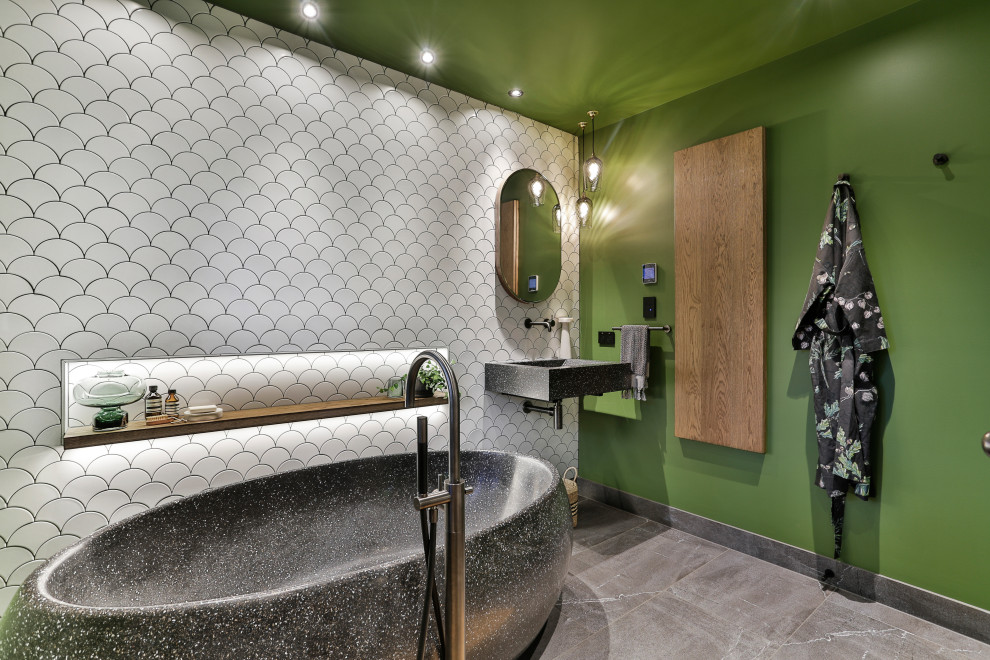 Стильный дизайн: ванная комната среднего размера в современном стиле с отдельно стоящей ванной, белой плиткой, керамической плиткой, зелеными стенами, полом из керамогранита, душевой кабиной, подвесной раковиной, столешницей терраццо, черной столешницей и серым полом - последний тренд