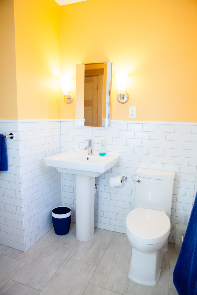 Foto di una stanza da bagno per bambini scandinava di medie dimensioni con vasca ad alcova, WC a due pezzi, piastrelle beige, piastrelle in ceramica, pareti gialle, pavimento con piastrelle in ceramica e lavabo a colonna