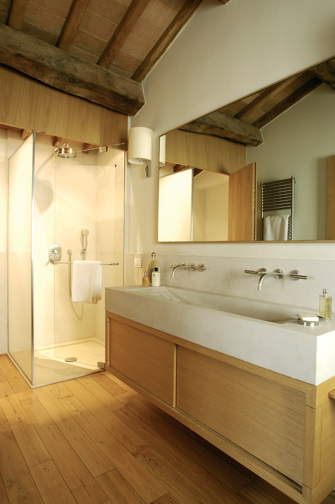 Rustic ensuite bathroom in London with a trough sink, flat-panel cabinets, light wood cabinets, a corner shower, white walls and medium hardwood flooring.