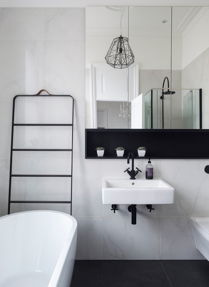 Example of a mid-sized trendy marble tile freestanding bathtub design in London with gray walls and a wall-mount sink