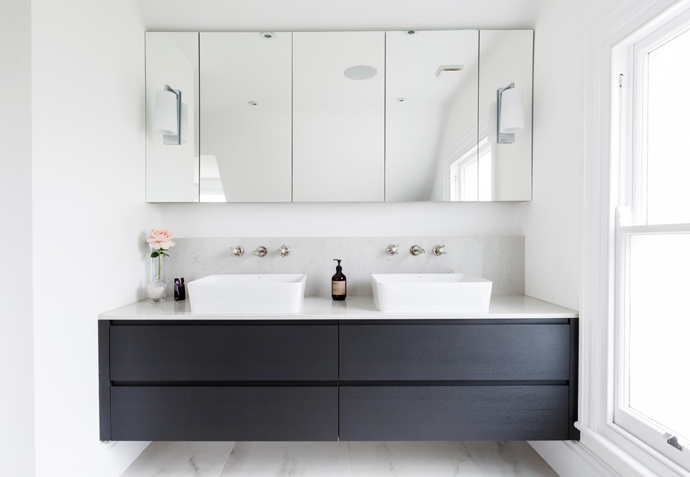 Immagine di una stanza da bagno design di medie dimensioni con ante lisce, ante blu, pareti bianche, pavimento in marmo, lavabo sospeso, top in marmo e pavimento grigio