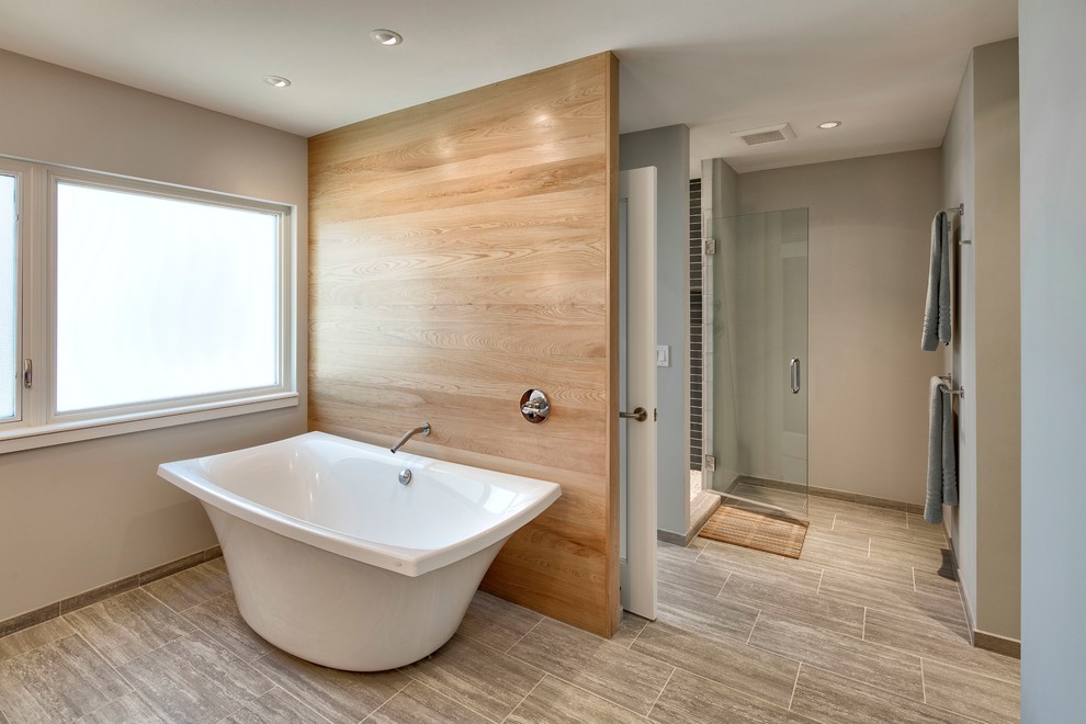 Пример оригинального дизайна: главная ванная комната среднего размера в стиле модернизм с плоскими фасадами, темными деревянными фасадами, отдельно стоящей ванной, душем в нише, бежевой плиткой, каменной плиткой, серыми стенами, полом из травертина, врезной раковиной и бежевым полом