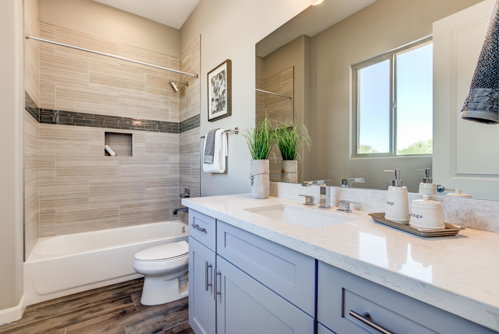 Inspiration for a large southwestern 3/4 beige tile and porcelain tile dark wood floor and brown floor bathroom remodel in Phoenix with shaker cabinets, gray cabinets, a two-piece toilet, beige walls, an undermount sink and limestone countertops