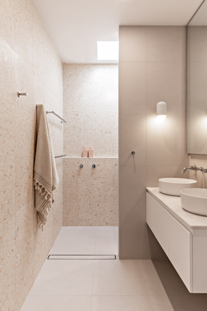 Свежая идея для дизайна: ванная комната в стиле модернизм с плоскими фасадами, белыми фасадами, душем без бортиков, бежевой плиткой, серым полом, открытым душем, белой столешницей, тумбой под две раковины и подвесной тумбой - отличное фото интерьера