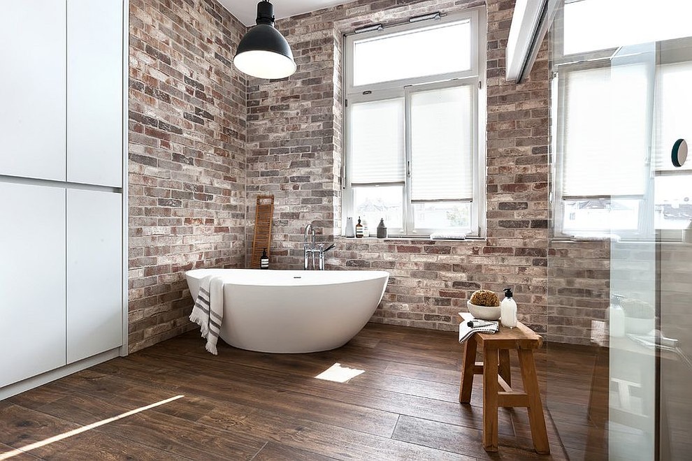 Cette photo montre une salle de bain moderne avec une baignoire indépendante, un carrelage multicolore, un mur multicolore, parquet foncé, un plan de toilette en bois et un sol marron.