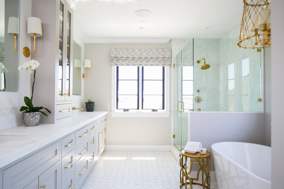 Идея дизайна: ванная комната в стиле неоклассика (современная классика) с фасадами в стиле шейкер, серыми фасадами, отдельно стоящей ванной, угловым душем, белой плиткой, плиткой из листового камня, бежевыми стенами, врезной раковиной, белым полом и душем с распашными дверями