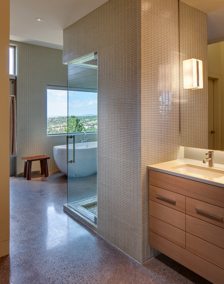 Modernes Badezimmer En Suite mit Unterbauwaschbecken, hellen Holzschränken, Quarzwerkstein-Waschtisch, freistehender Badewanne, grünen Fliesen, Glasfliesen und Betonboden in Albuquerque