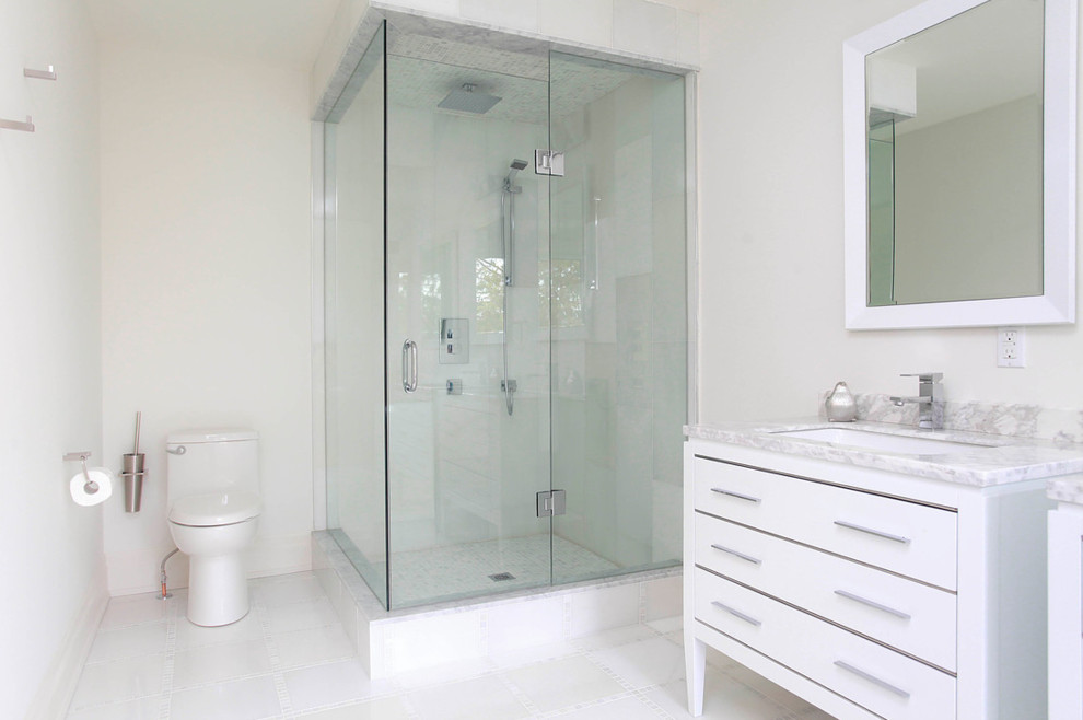 Photo of a medium sized modern ensuite bathroom in Toronto with flat-panel cabinets, white cabinets, a freestanding bath, a walk-in shower, a one-piece toilet, beige tiles, stone tiles, white walls, ceramic flooring, a trough sink and tiled worktops.
