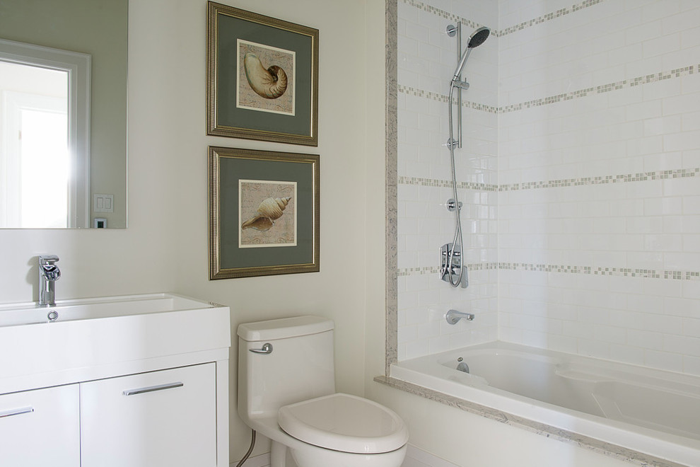 Inredning av ett modernt mellanstort en-suite badrum, med släta luckor, vita skåp, ett fristående badkar, en öppen dusch, en toalettstol med hel cisternkåpa, beige kakel, stenkakel, vita väggar, klinkergolv i keramik, ett avlångt handfat och kaklad bänkskiva
