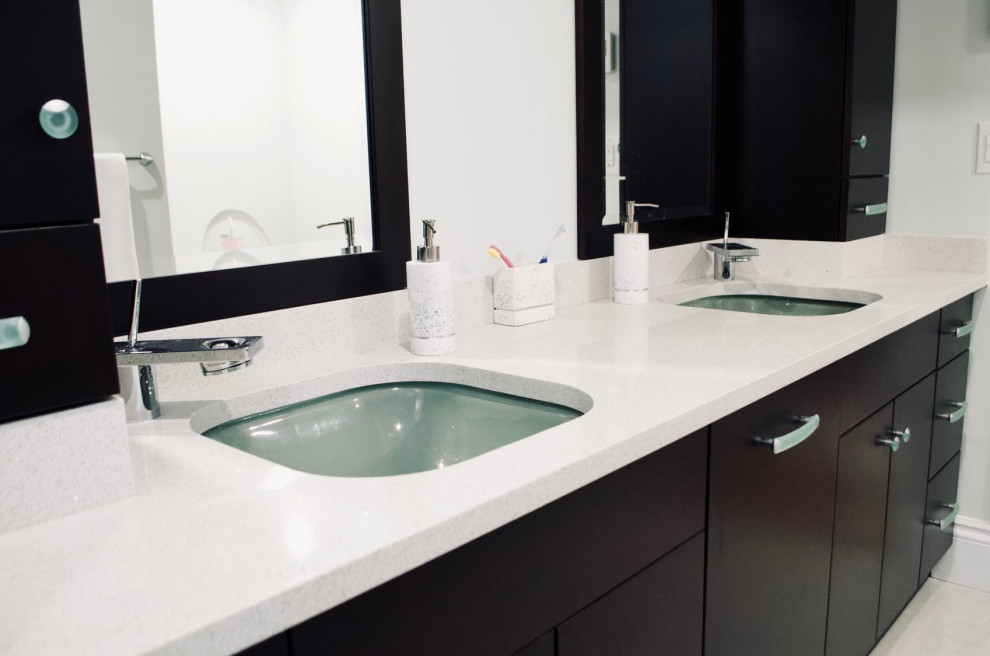 Photo of a medium sized traditional ensuite bathroom in Toronto with flat-panel cabinets, dark wood cabinets, an alcove shower, a two-piece toilet, black tiles, porcelain tiles, porcelain flooring, a submerged sink, solid surface worktops, beige floors, a hinged door, beige worktops, double sinks and a built in vanity unit.