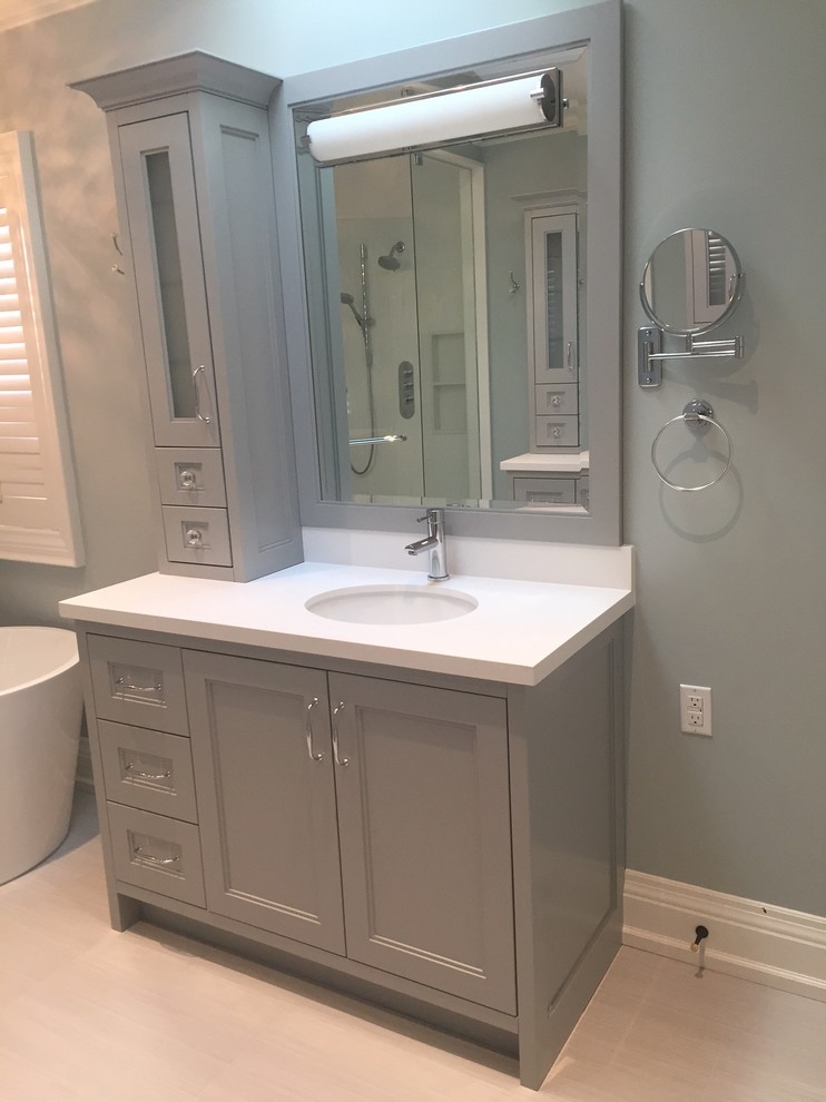 Design ideas for a large contemporary ensuite bathroom in Toronto with shaker cabinets, grey cabinets, a freestanding bath, a corner shower, a one-piece toilet, grey tiles, porcelain tiles, grey walls, porcelain flooring, a submerged sink and engineered stone worktops.