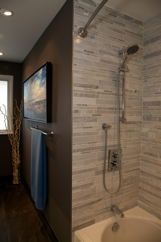 Medium sized modern ensuite bathroom in Toronto with flat-panel cabinets, dark wood cabinets, a built-in bath, a shower/bath combination, a two-piece toilet, grey tiles, stone tiles, grey walls, porcelain flooring, an integrated sink, solid surface worktops, brown floors, a shower curtain and white worktops.