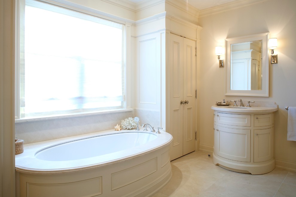Cette photo montre une salle de bain principale chic de taille moyenne avec un placard avec porte à panneau encastré, des portes de placard beiges, une baignoire encastrée, une douche à l'italienne, WC à poser, un carrelage beige, du carrelage en marbre, un mur beige, un sol en marbre, un lavabo encastré, un plan de toilette en marbre, un sol beige, une cabine de douche à porte battante et un plan de toilette beige.