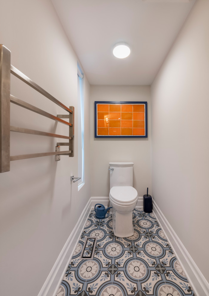 На фото: туалет среднего размера в современном стиле с плоскими фасадами, фасадами цвета дерева среднего тона, унитазом-моноблоком, белыми стенами, полом из цементной плитки, монолитной раковиной и разноцветным полом с